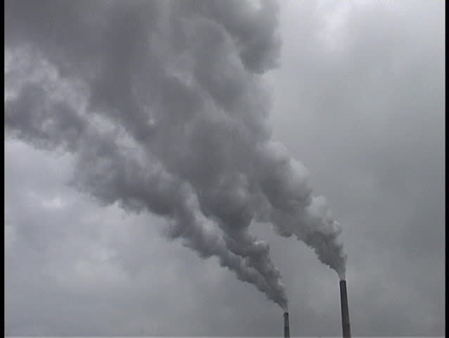  smokestacks with dark, grey smoke billowing out of the tops.