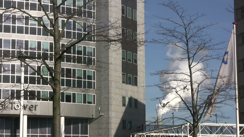 Modern Office building with smokestack in the background.