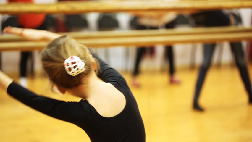 cute little girl repeats movement arms of adults dancers standing in mirror