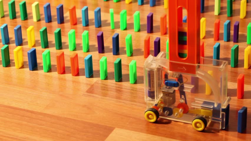 Toy machine moves and put colored domino blocks, view from above 