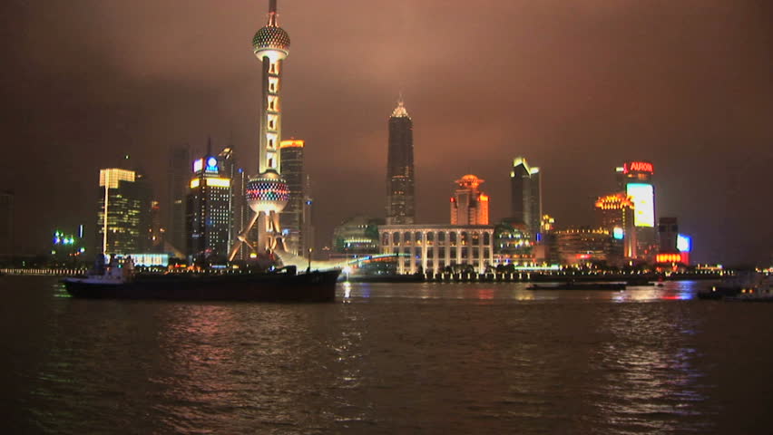 Lit up boats pass Pudong, Shanghai, China, on the River Huangpu, skyline at night, time lapse