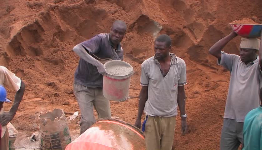 KENYA, AFRICA - CIRCA 2009: Men throw cement and aggregate into a cement mixer circa 2009 in Kenya.