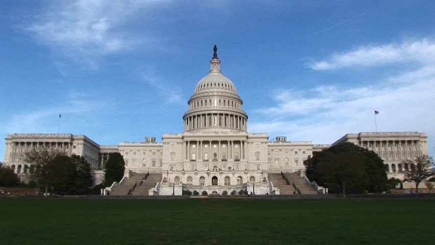From a Wide shot of the eastern facade of the U.S. Capitol building in Washington, DC, the camera zooms in on the building's landmark rotunda and unique iron dome.