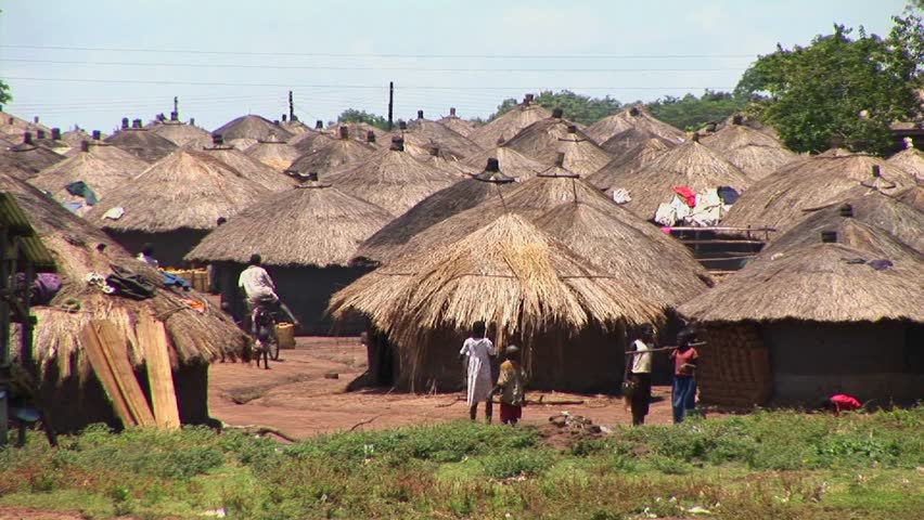  People walk around traditional village circa 2009 in Uganda.
