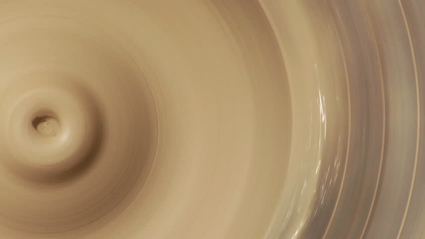 CU of potter wheel, male hand enters frame to interfere