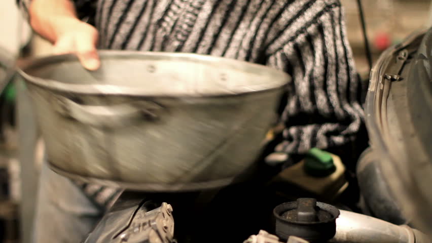 technician removes the oil filter on a car. 
