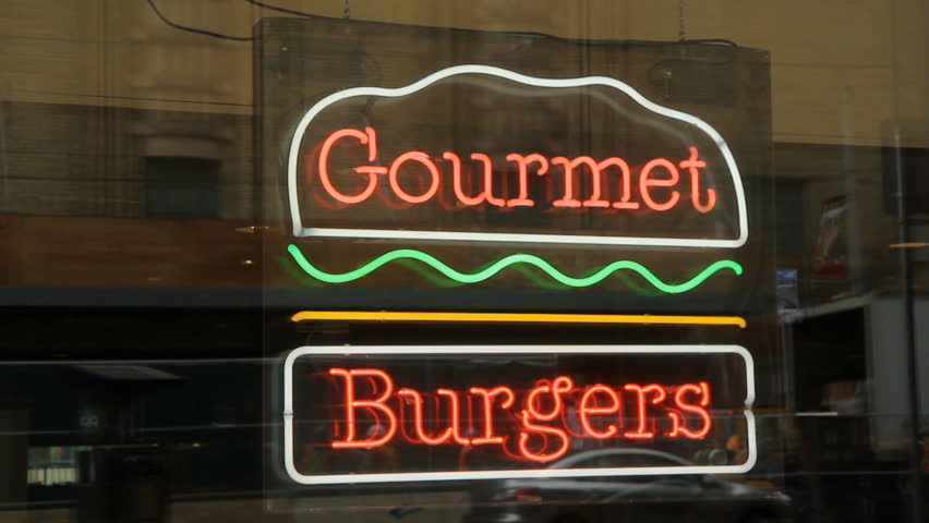 Gourmet burgers sign. Neon burger sign in restaurant window. Reflections of traffic. 