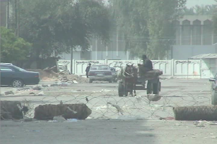 BAGHDAD, IRAQ - CIRCA 2009: An oxcart makes its way across central Baghdad as veiled Muslim women pass by.