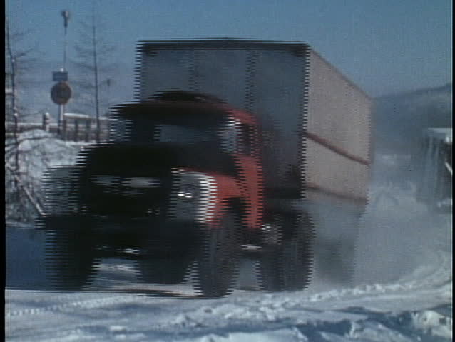 Long haul trucks move through the snow in this archival shot.
