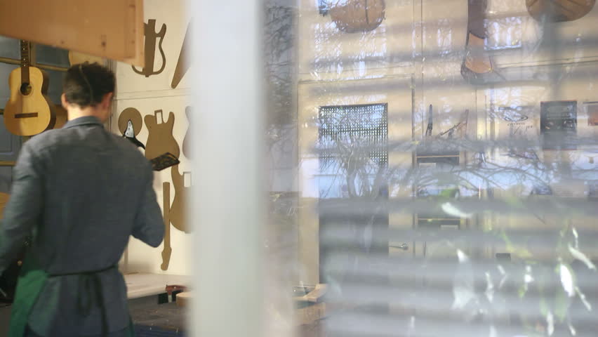 Man working as artisan in Italian workshop with guitars and musical instruments