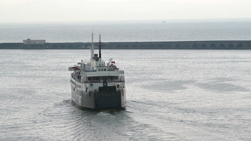 Ferry boat departing port at Palma Mallorca into the Mediterranean Sea. Stormy day with low clouds and haze. 