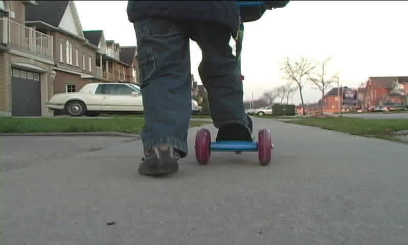 Boy riding a scooter on sidewalk