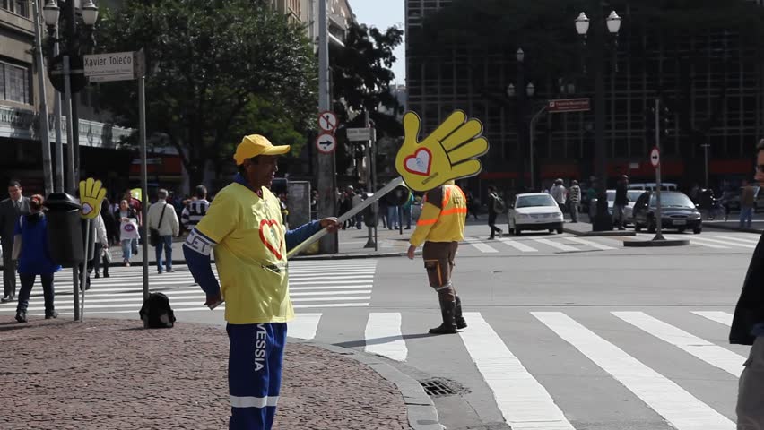 SAN PAULO, BRAZIL - CIRCA JUNE 2011: A man at an intersection holds a sign promoting safety and love circa June 2011 in San Paulo.