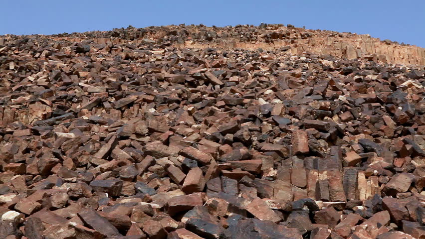 Low angled tilt-up of the rocky hillside to blue sky at Ha-Minsara (The Carpentry Shop), a geological formation in the Mitzpe Ramon Crater in Israel. 