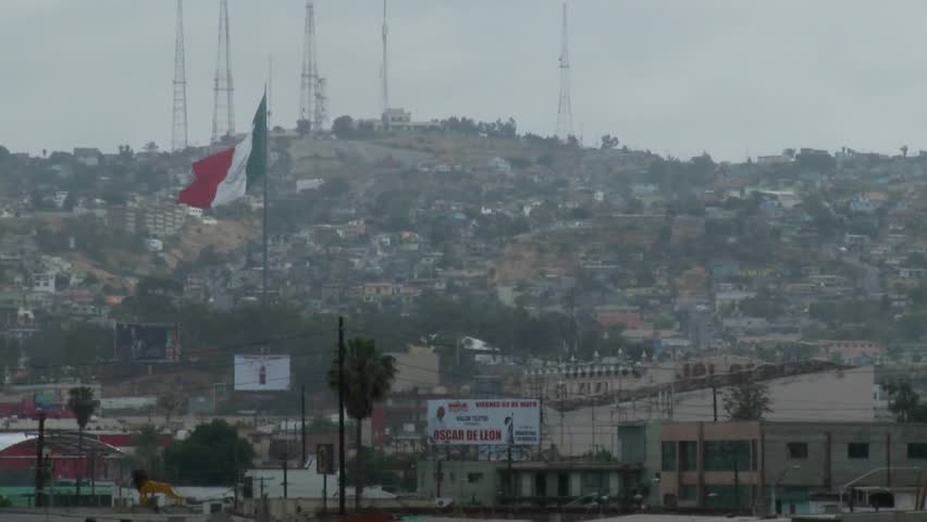 the Mexican flag is seen waving above downtown Tijuana Mexico.