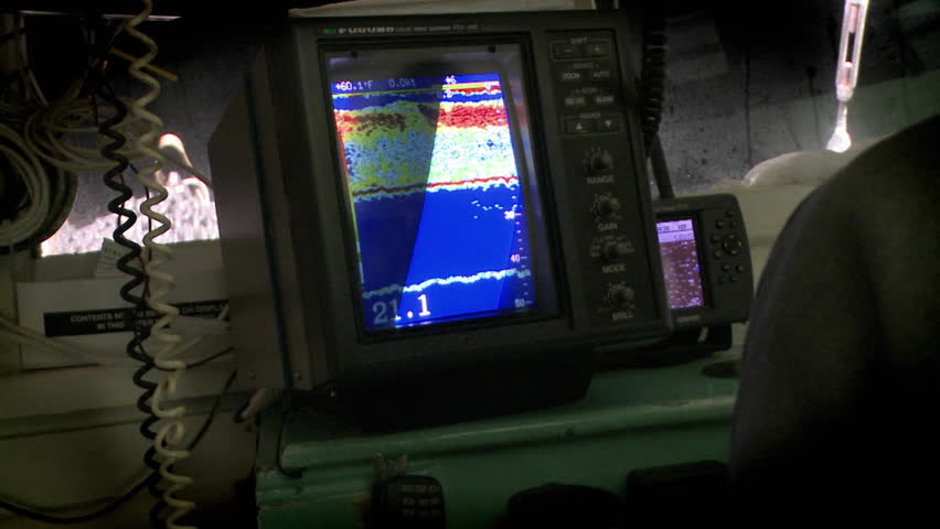 A man points to a sonar display on a small vessel.