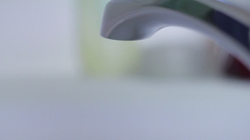 Silver faucet turned on filling bathtub with water