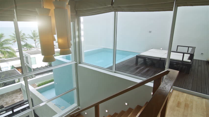 Pan shot of a luxury villa interior. Overlooking the outdoor tropical scene.