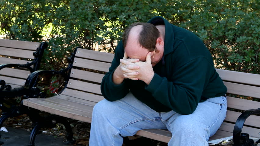Man sit on a park bench in a state of depression.