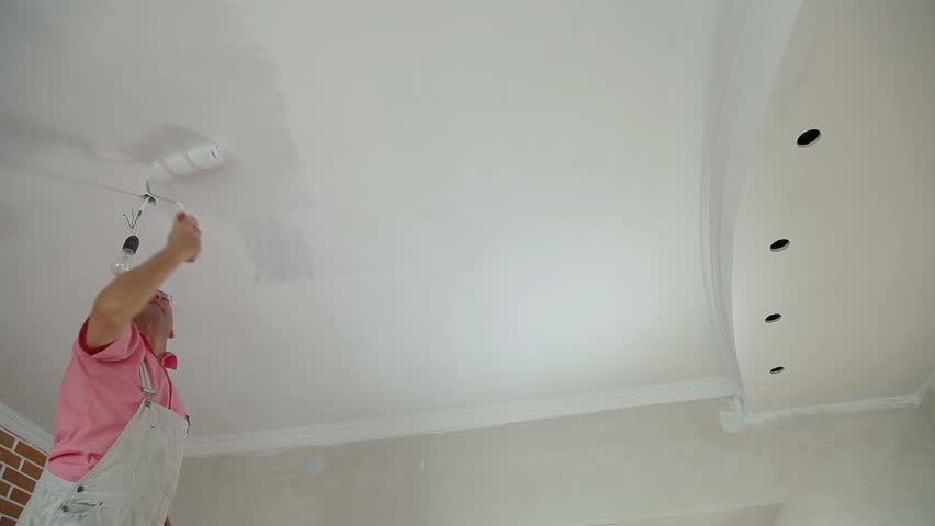 man painting the ceiling, using a paint roller