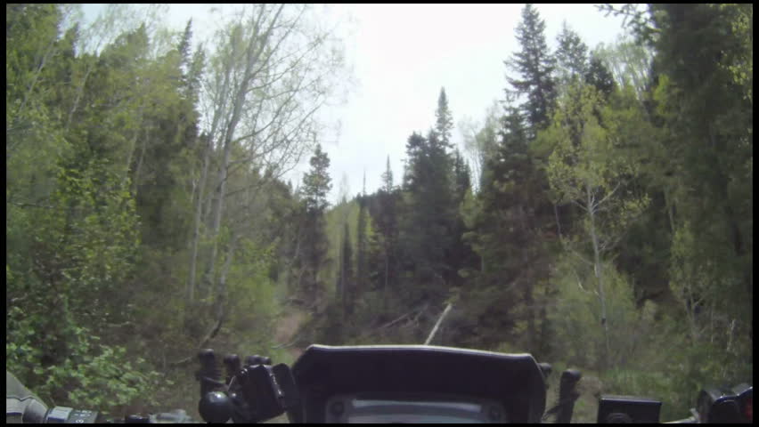ATV riding on a narrow mountain trail in forest and crossing streams. Rough wilderness riding and exploring nature for fun and recreation. Central Utah, Wasatch mountains.