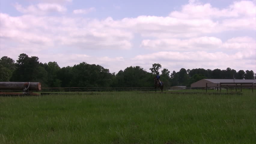 Young woman galloping and jumping her horse in an open field