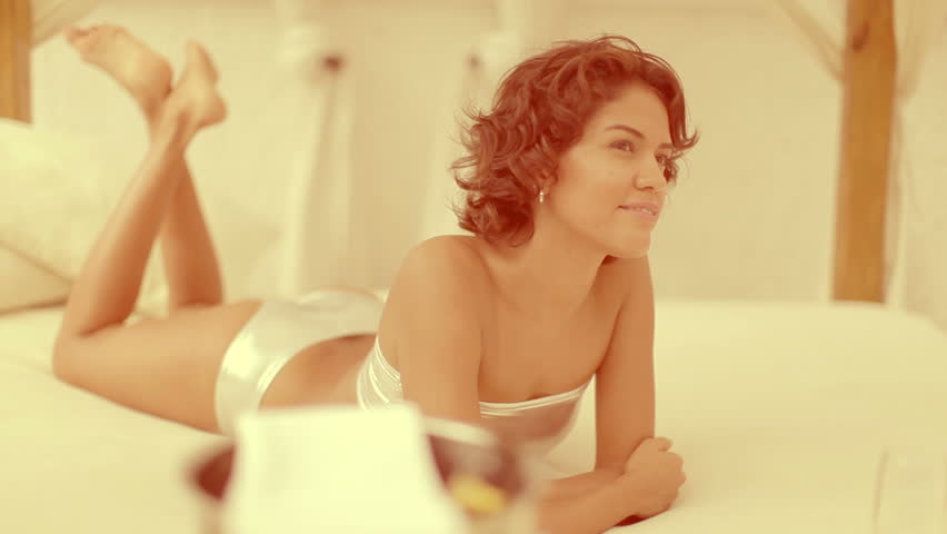 a sexy woman in a bikini drinks champagne on a daybed around a pool
