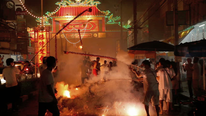 PHUKET, THAILAND - OCTOBER 5: Volunteer in vegetarian procession wades through firecrackers explode from people who join in the festival on October 5, 2011 in Phuket Thailand.