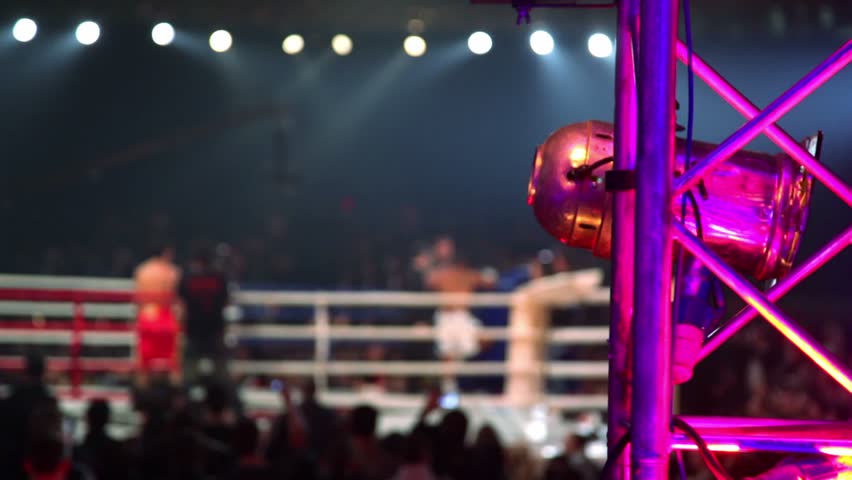 Fighters on boxing ring unfocused, light projector shell on metal hardware closeup