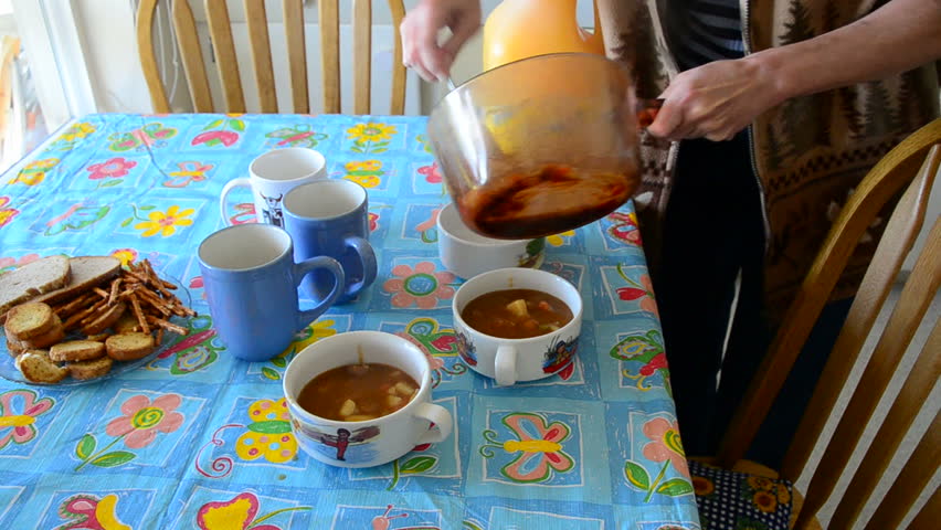 tomato soup being served and poured into a bowl with a ladle with bread.