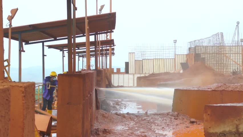 Worker blasts water to separate iron ore from soil