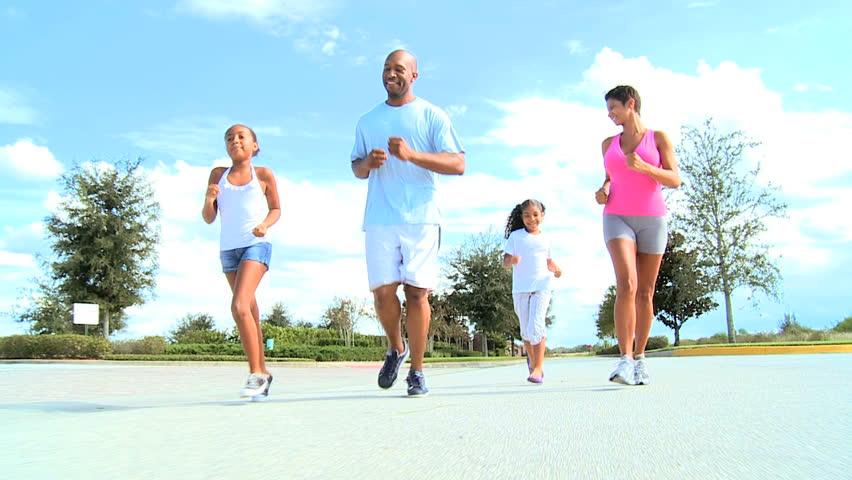 Happy young ethnic family jogging for fun on suburban roads
