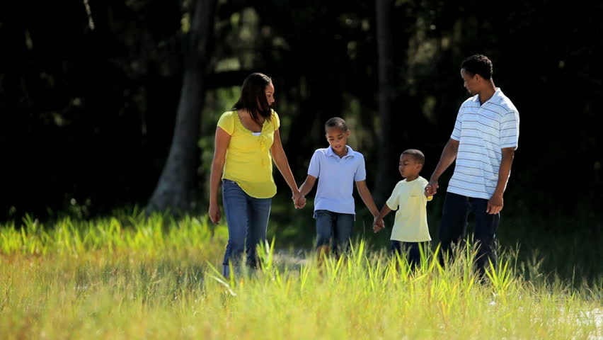 Young african american family walking together through parkland