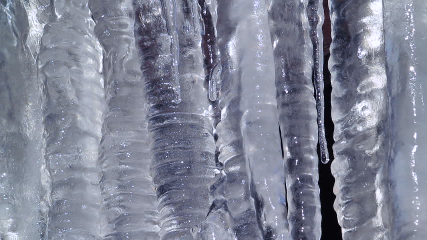 Icicles hanging from roof begin to melt with the coming of spring. Extreme close up.