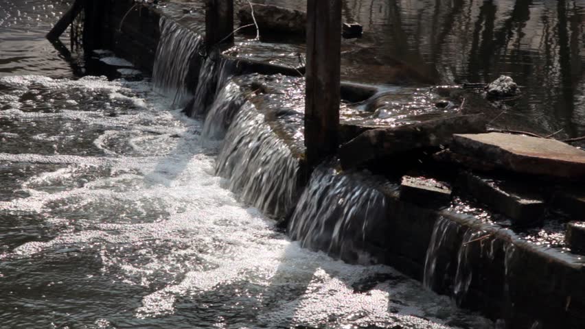 Water flow over big stones on dam in river, closeup view
