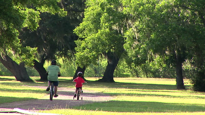 father and son riding their bikes through a park