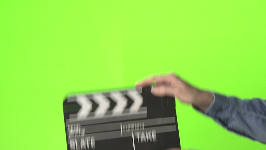 Woman slating a take with clapper board on green screen, medium shot