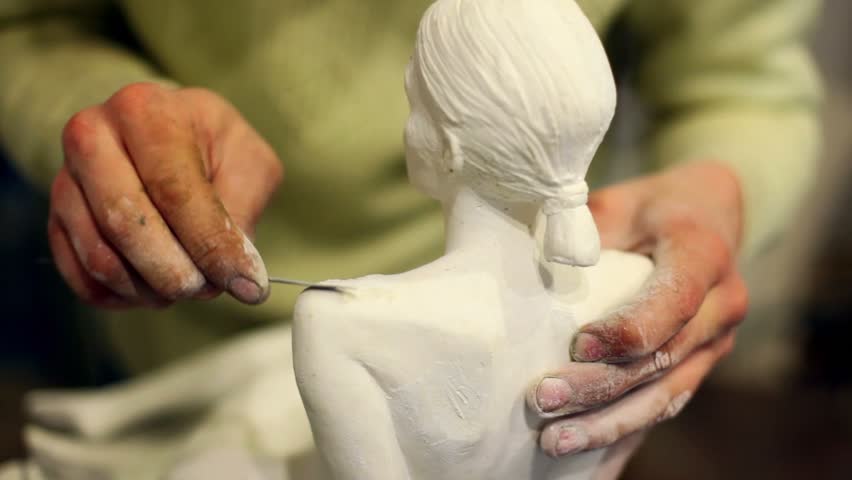Sculptor corrects arm of female figurine by special tool