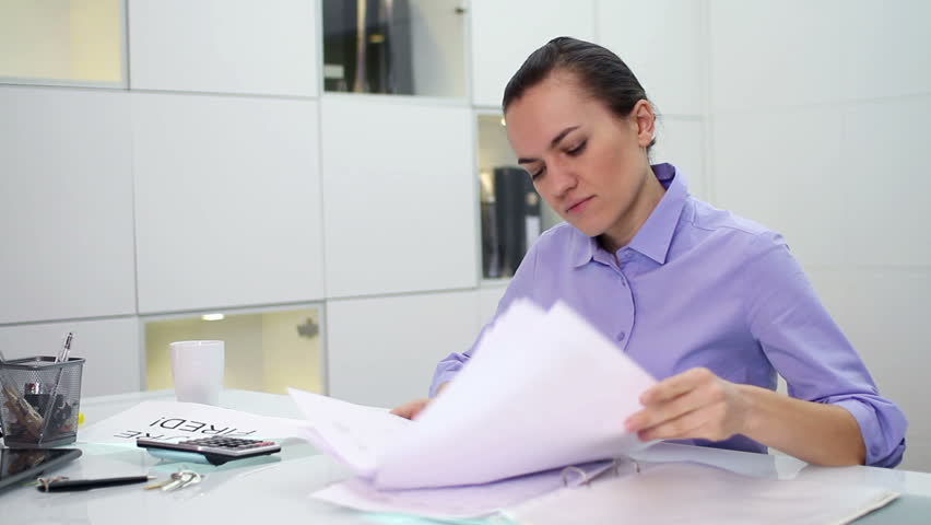 Young businesswoman overwhelmed by too much paperwork in office