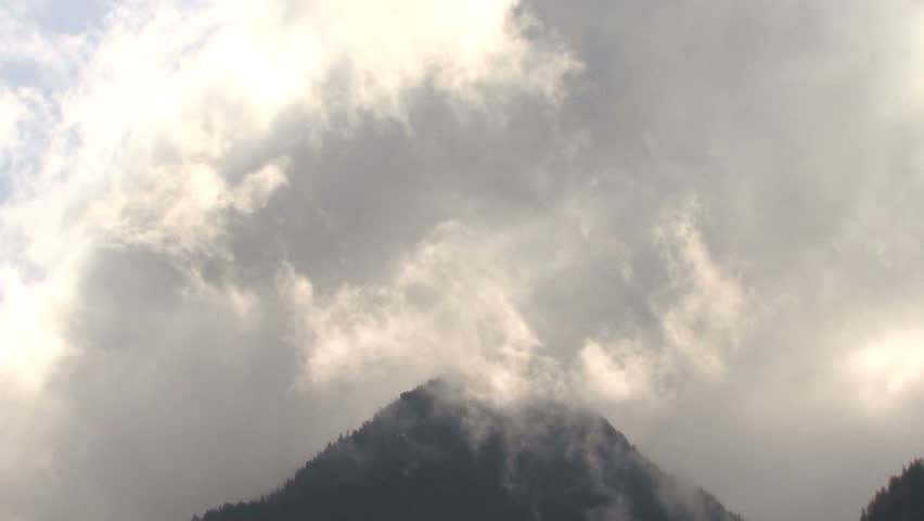 Mountain peak partly hidden by rising cloud banks