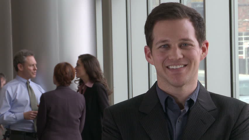 Smiling young male professional in front of coworkers (2 of 2)