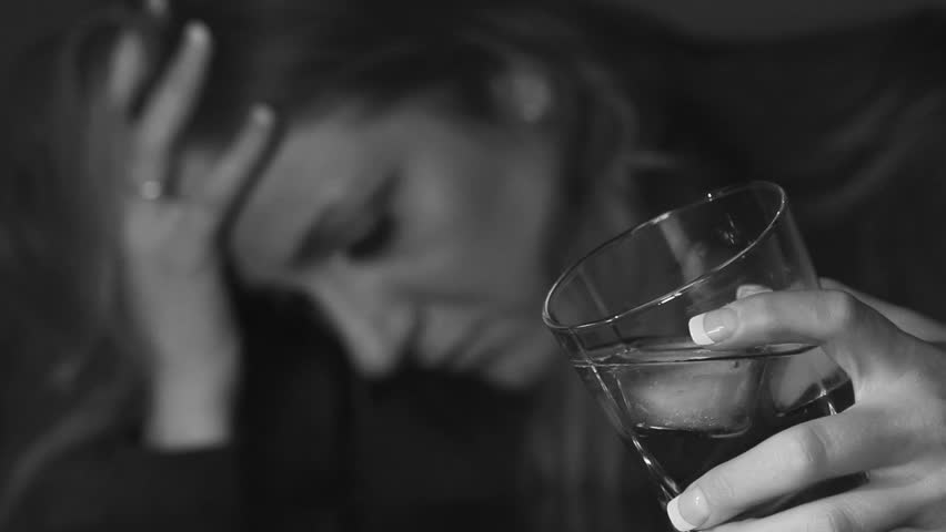 Young woman drinking alcohol. Glass in sharp focus. Shallow DOF. Black and white.
