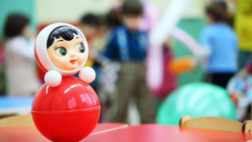 roly-poly toy on table, then panorama and focus moved to children playing in kindergarten