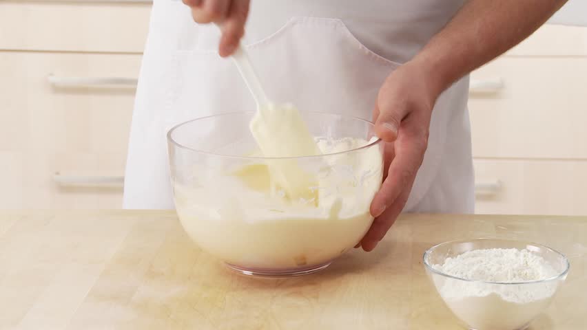 Beaten egg white being mixed with egg yolk cream and flour being added