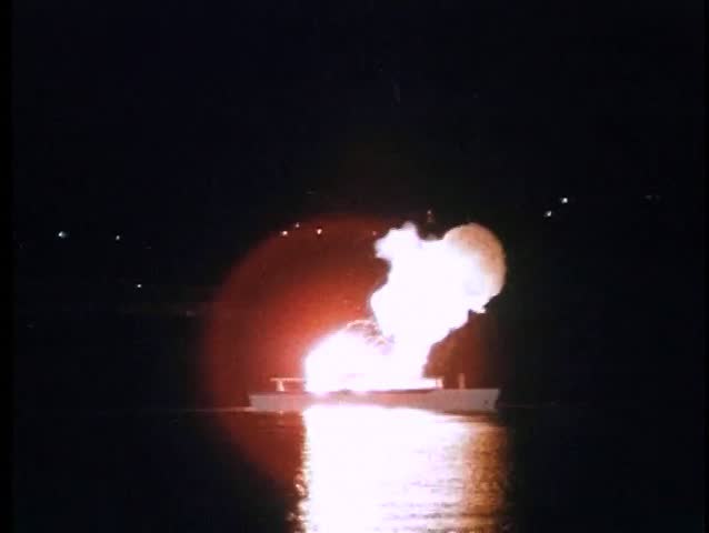 Wide shot of yacht exploding at night in port