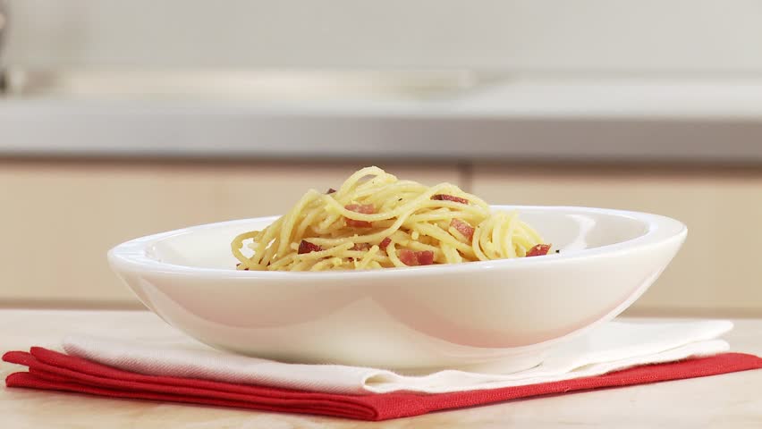 Spaghetti alla Carbonara being sprinkled with pepper