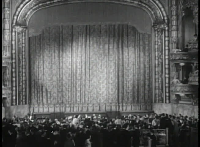 Wide shot of audience in theater waiting for performance to begin