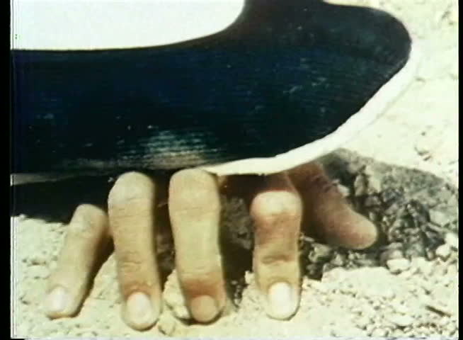 Close-up of foot in Chinese slipper stepping on hand
