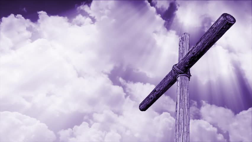 wooden cross backed by time lapse motion clouds with shining, penetrating shafts of light - violet tone