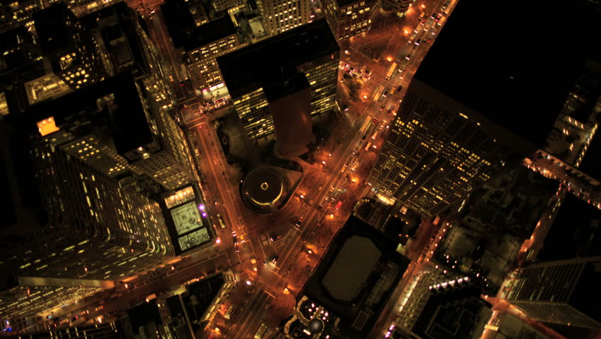 Aerial night vertical view of lights on skyscrapers and streets in an urban city